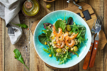 Diet menu, Vegan food. Healthy salad with quinoa, arugula, Shrimps and olives on a wooden rustic table. Top view flat lay background.