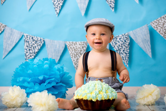 Little baby boy, celebrating his first birthday with smash cake party, studio isolated shot on blue