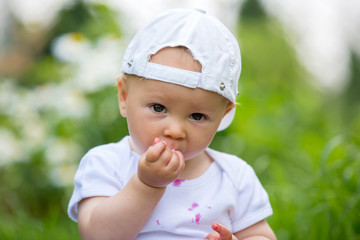 Sweet little child, baby boy, eating cherries in garden, enjoying tasty fruit