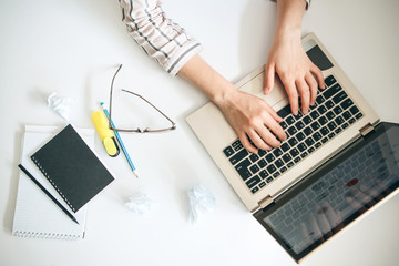 Top view of female hands working behind a laptop in a working office or home office. Or the student does the lessons or exercises.