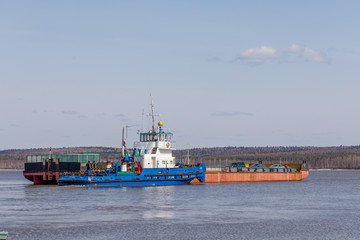 The movement of the ferry through the deep Urals River in Russia in the sunny spring afternoon. Working crossing.