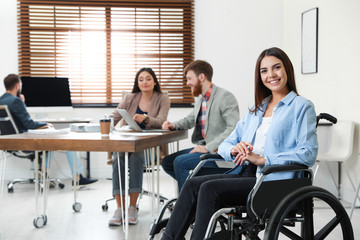 Young woman in wheelchair with colleagues at office