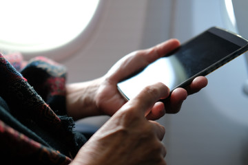 Obraz premium hand holding mobile smart phone on airplane