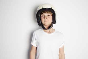 Portrait of young handsome cheerful teen in white tshirt preparing to ride a motorcycle isolated on white background