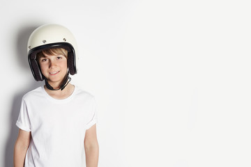 Happy young cute cheerful teen boy in white tshirt draming to ride a motorcycle isolated on white background