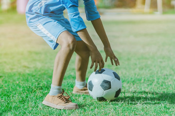 Asian boys practice kicking the ball to score goals in the public football field.