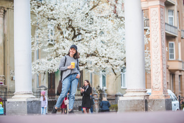 young stylish woman walking by street with coffee cup