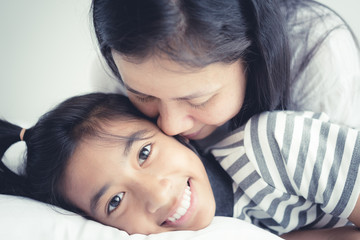 Portrait picture of love family mother on the kiss  daughter; Cute girl smile beautiful and happy on bed.