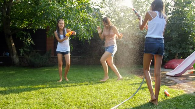 Slow motion video of family having water battle with garden hose and water guns at house backyard