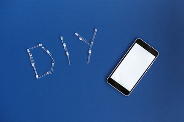 DIY word from diode and phone on a blue background. DIY words for Do It Yourself concept. place for...