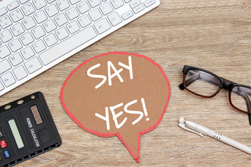sey yes on speech bubble on wooden table