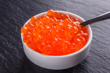 red caviar in a bowl on a dark stone background