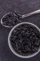 Fototapeta na wymiar black caviar in a bowl on a dark stone background