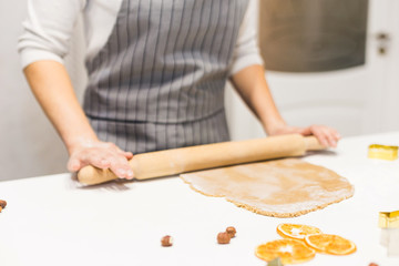 Obraz premium Young pretty woman prepares the dough and bakes gingerbread and cookies in the kitchen. Merry Christmas and Happy New Year.