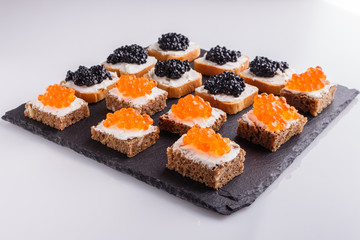 Snack with red and black caviar on a stone plate