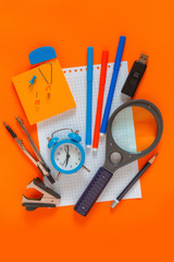 Back to school. Pattern of modern design with school supplies pencils, felt-tip pens, alarm clock, notebook copy space, school mock-up poster on an orange coral blackboard background
