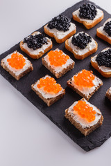 Snack with red and black caviar on a stone plate