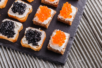 Snack with red and black caviar on a stone plate