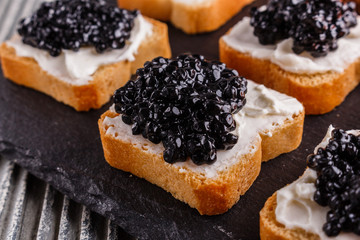 Snack with red and black caviar on a stone plate