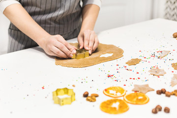 Young pretty woman prepares the dough and bakes gingerbread and cookies in the kitchen. Merry Christmas and Happy New Year.