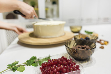 Confectioner smooths white cream on a biscuit cake with a cooking spatula. The concept of homemade pastry, cooking cakes.