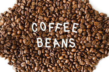 Coffee beans on white background with white inscription in middle.