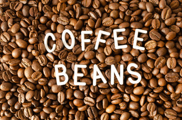 Background with coffee beans with white inscription in the middle.