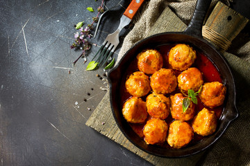 Homemade Beef meatballs in tomato sauce in a frying pan on dark stone table.  Flat lay, top view background. Copy space.