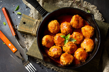 Homemade Beef meatballs in tomato sauce in a frying pan on dark stone table.  Flat lay, top view background.