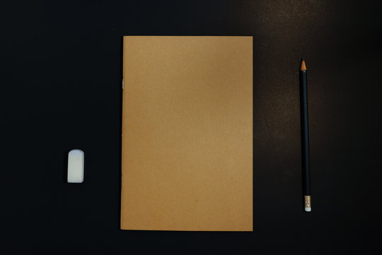 Notebook, pencil and eraser on black background
