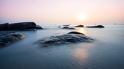 Fototapeta na wymiar Sunrise on the beach, black rocks, beautiful light in the morning