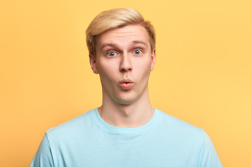 handsome man with funny facial expression learning to whistle., singing a song, flirting with a girl. close up photo. islated yellow background, emotion concept