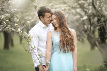 A Kissing newlywed couple spending time in blooming garden.