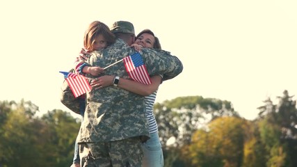 Hugs of the american soldier with familty. Father came back from the military oparation, extremely happy familiy embracing in the park. - Powered by Adobe
