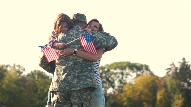 Hugs of the american soldier with familty. Father came back from the military oparation, extremely happy familiy embracing in the park.