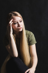 Sad young woman going to cry in a black background