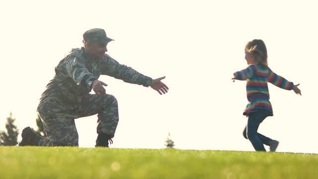 Daughter runs into the arms of her father soldier. Military father waiting for his daughter and hugging.