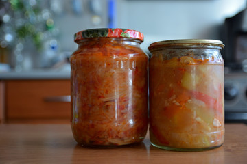 Jars with homemade canned salads on the table against the background of the kitchen