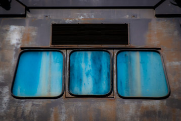 Tre finestre blu sulla facciata di una fabbrica abbandonata 