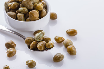 Pickled capers on a white acrylic background