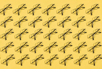 many glasses lying on the yellow table.bad eyesight. seamless round glasses. game,collection, composition
