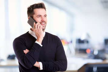 Businessman standing in the office and talking with somebody on his mobile phone