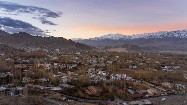 4K Timelapse of cityscape and high snow mountain range on rural desert landscape and Leh Palace with beautiful sunrise and amaizing cloud moving as background, Leh, Ladakh, India