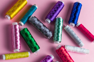 colorful sewing threads isolated on pink background. top view photo.seamstress's tool.