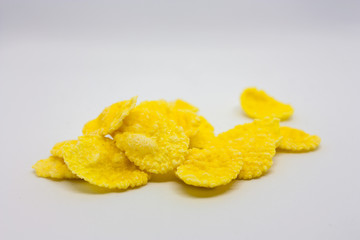A bunch of yellow crispy cornflakes on a white background close-up.