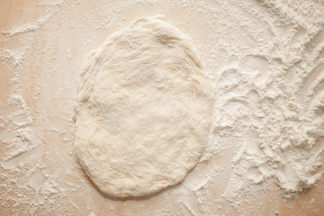 Ball of pizza dough on a rustic wooden background with dusting of flour