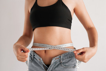 Slender girl with a tape measure around the waist