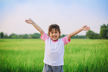 Smiley face of kid who playing and learning by natural exploration at the green rice field in the...