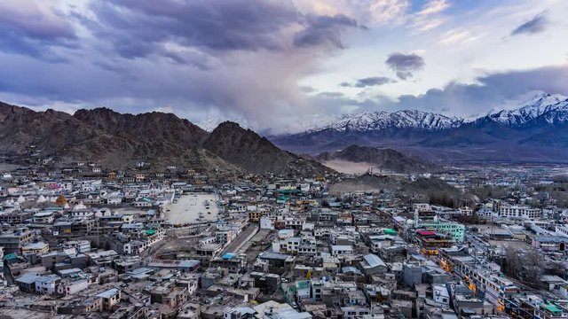 4K Timelapse of cityscape and high snow mountain range on rural desert landscape and Leh Palace with beautiful blue cloudy sky and amaizing cloud moving as background, viewed of rooftop Leh,India