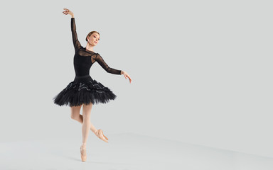 Woman ballet dancer over gray background.